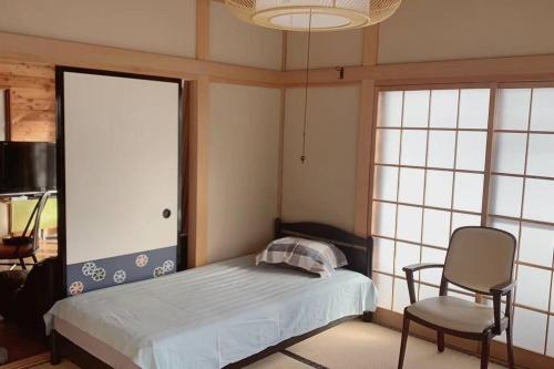 a bedroom with a bed and a chair and a chandelier at 一番館※温泉街に近く、心が落ち着く別荘地同樺順荘 in Kusatsu