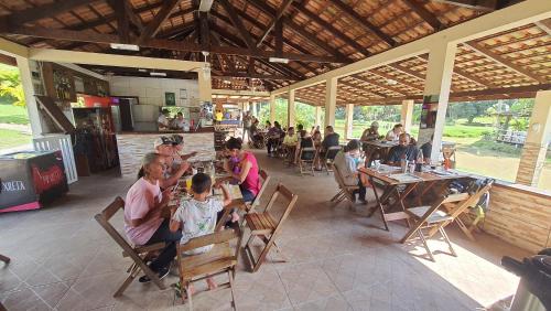 un grupo de personas sentadas en mesas en un restaurante en RECANTO NA MATA, en Morretes