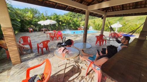 RECANTO NA MATA في موريتيس: مجموعة من الناس يجلسون على الطاولات بالقرب من حمام السباحة