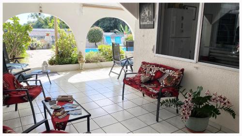 een patio met stoelen en een tafel op een tegelvloer bij Mahina's Lodge in Mahina