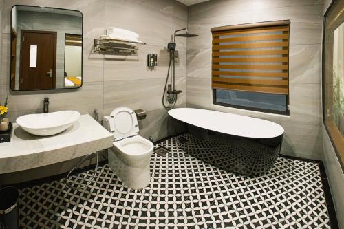 a bathroom with a tub and a toilet and a sink at Napoli Hotel in An Khê