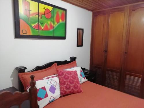 a bedroom with a bed and a painting on the wall at Habitaciones en Edificio Ginebra Manizales in La Linda