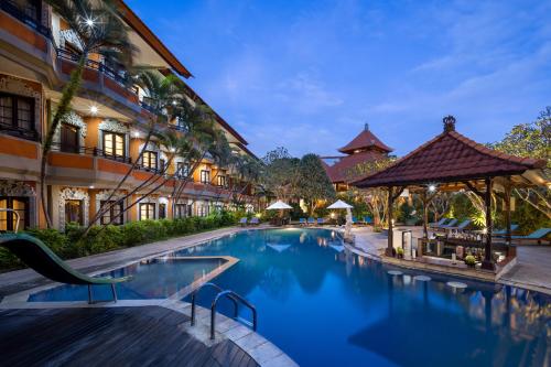 a swimming pool in front of a building at Adi Dharma Hotel Kuta in Kuta