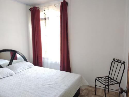 a bedroom with a bed and a chair next to a window at Casa Tangara in San Isidro de El General