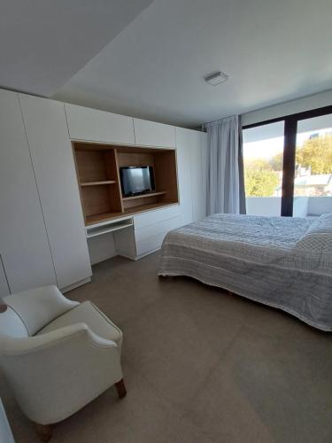 um quarto com uma cama, uma cadeira e uma televisão em Apart Playa Grande em Mar del Plata
