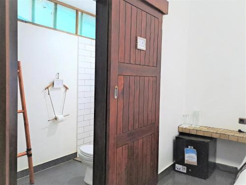 a bathroom with a wooden door next to a toilet at Katara Gili, Boutique Rooms and Bungalows in Gili Trawangan
