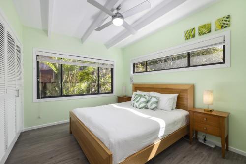 a bedroom with a large bed and two windows at Pandanus On Emerald in Emerald Beach