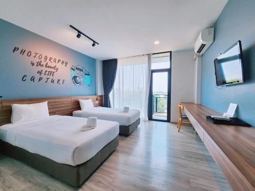 een hotelkamer met 2 bedden en een televisie bij R2 Hotel in Nakhon Phanom
