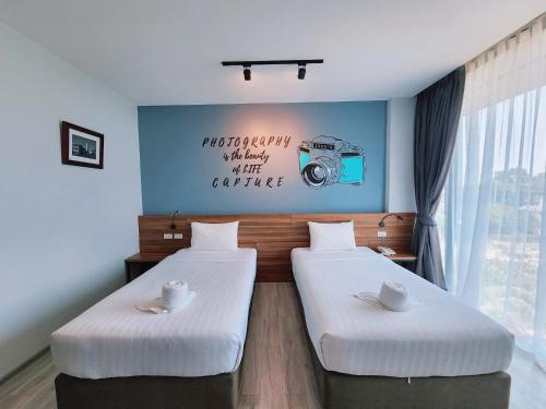 two beds in a room with a camera on the wall at R2 Hotel in Nakhon Phanom