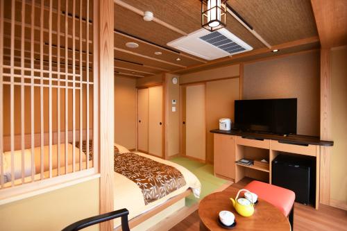 a hotel room with a bed and a tv and a table at Kasuitei Ooya in Fujikawaguchiko