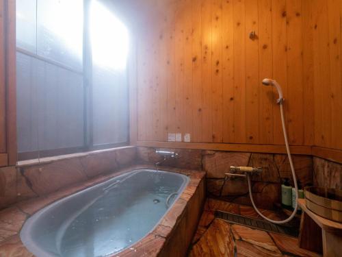 a bath tub in a bathroom with a wooden wall at Tsuruya / Vacation STAY 59066 in Miyaji