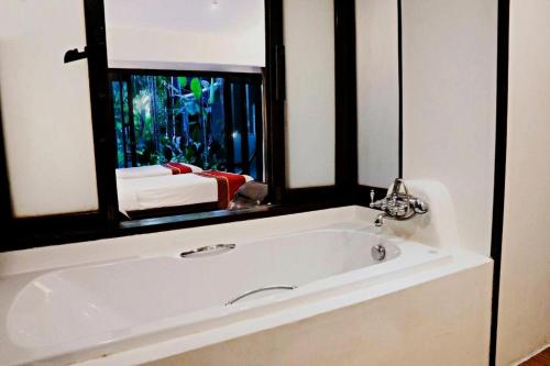 a bathroom with a white bath tub with a mirror at Yantarasri Resort in Chiang Mai