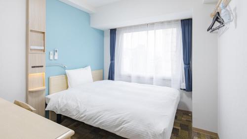 a bedroom with a white bed and a window at Toyoko Inn Kyoto Nijojo Minami in Kyoto