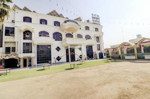 密拉特的住宿－CAPITAL O74359 Hotel Mukut Mahal，前面有长椅的白色大建筑