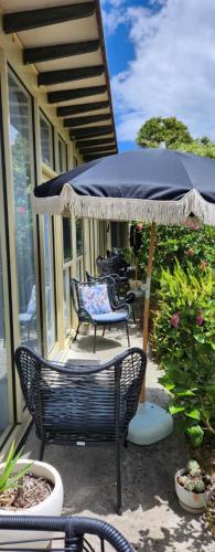 a patio with two chairs and an umbrella at Peninsula Beach Motel in Rosebud