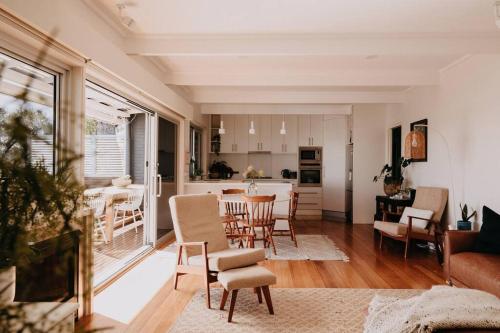 a living room with a table and chairs and a kitchen at Olga and Alma - The Coastal Retreat in Pambula Beach