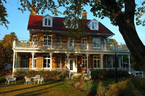 a large brick house with a balcony on top of it at Chez Truchon Bistro-Auberge in La Malbaie