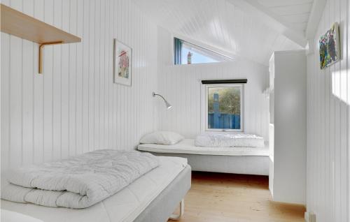 a white bedroom with two beds and a window at Åbo in Klitmøller
