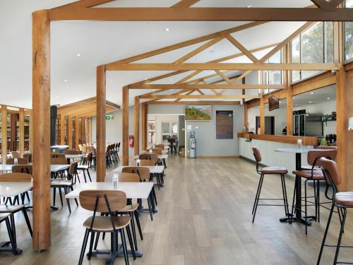 Wilpena Pound Resort في فلينديرس رينجيس: غرفة طعام بها طاولات وكراسي وعوارض خشبية