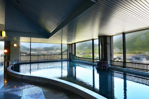 a large swimming pool in a building with windows at Yufuin Hotel Shuhokan in Yufuin