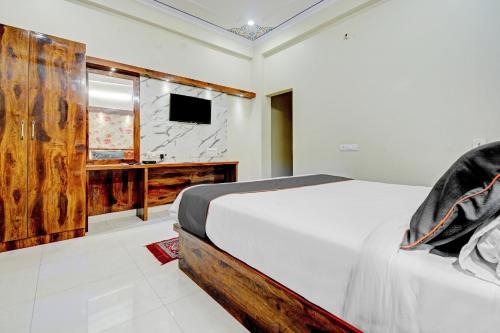 1 dormitorio con 1 cama blanca y TV en Hotel Tejesvi, en Jaipur