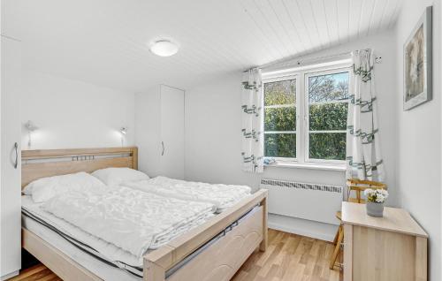 een witte slaapkamer met een groot bed en een raam bij Beautiful Home In Prst With House Sea View in Stavreby