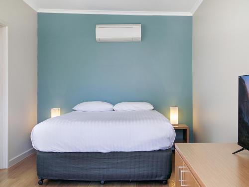 a bedroom with a bed with a blue wall at Wilpena Pound Resort in Flinders Ranges