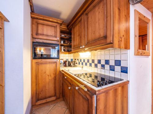 Elle comprend une petite cuisine avec des placards en bois et un évier. dans l'établissement Appartement cosy à Tignes · Proche pistes & commerces · Balcon · 4 pers. · 3*** - FR-1-502-392, à Tignes