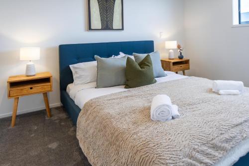 um quarto com uma cama grande e uma cabeceira azul em The Tranquil Terrace - Zen zone 2 bed 2 bath em Christchurch