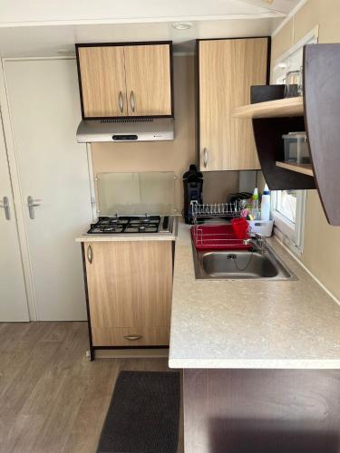 une petite cuisine avec un évier et une cuisinière dans l'établissement Mobil-Home des Iscles, à La Roque-dʼAnthéron