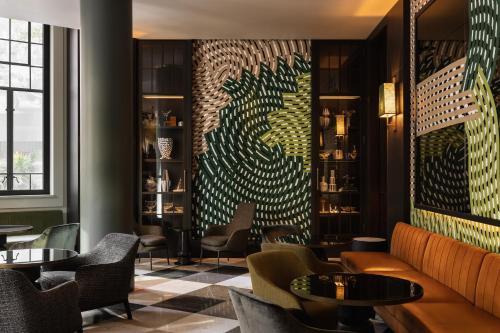 a restaurant with tables and chairs and a wall with a mural at Capella Sydney in Sydney