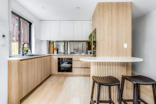 una cocina con armarios de madera, encimera y taburetes en Kahlo Bondi - Luxury Escape - 1 Bedroom Furnished Apartments en Sídney