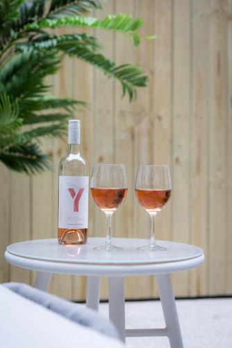 two wine glasses on a table with a bottle of wine at Kahlo Bondi - Luxury Escape - 1 Bedroom Furnished Apartments #4 in Sydney