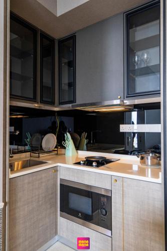 a kitchen with wooden cabinets and a stove top oven at Millerz Square Mana-Mana Suite in Kuala Lumpur