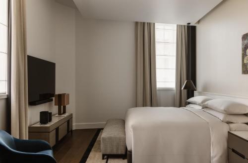 a bedroom with a bed and a tv and a chair at Capella Sydney in Sydney