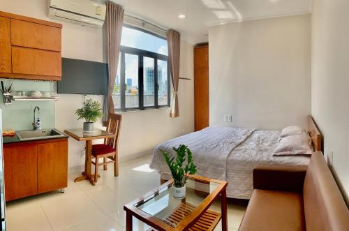 a bedroom with a bed and a table and a kitchen at căn hộ Lý Chính Thắng in Ho Chi Minh City