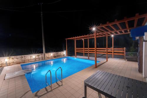 una piscina por la noche con una mesa y un banco en private house noko en Isla Miyako