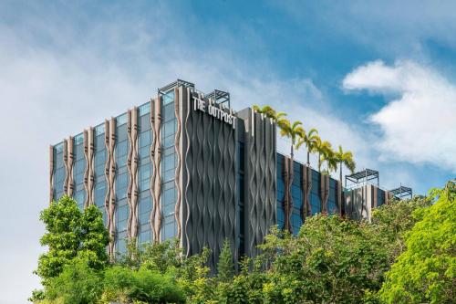 a tall building with palm trees in front of it at The Outpost Hotel Sentosa by Far East Hospitality in Singapore