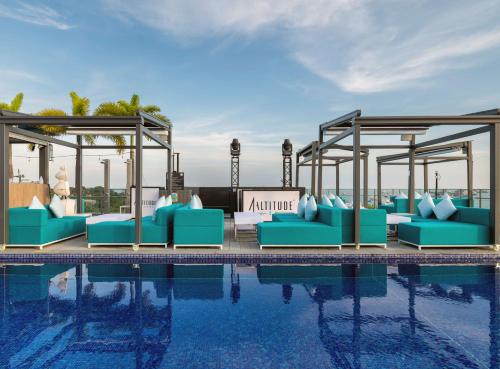 a pool with blue lounge chairs next to the water at The Outpost Hotel Sentosa by Far East Hospitality in Singapore