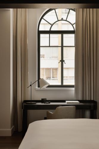 a bedroom with a bed and a desk and a window at Capella Sydney in Sydney