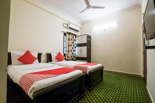 sypialnia z 2 łóżkami i czerwonymi poduszkami w obiekcie OYO Flagship13162 Swiss Legrand w mieście Hajdarabad