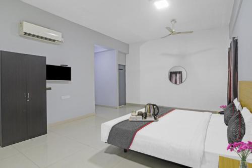 a white bedroom with a bed and a tv at Townhouse De Alphabet in Hyderabad