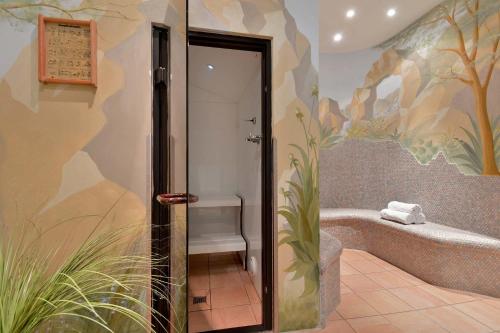 a bathroom with a bath tub with a painting on the wall at Hotel Glockenstuhl in Gerlos