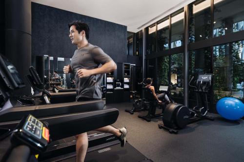 a man running on a treadmill in a gym at The Outpost Hotel Sentosa by Far East Hospitality in Singapore