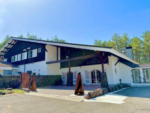 a large white house with a gambrel roof at HOLIDAY VILLA Hotel & Resort KARUIZAWA in Tsumagoi
