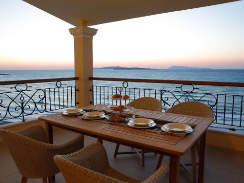 a wooden table on a balcony with a view of the ocean at Pictures Suites in Agios Stefanos