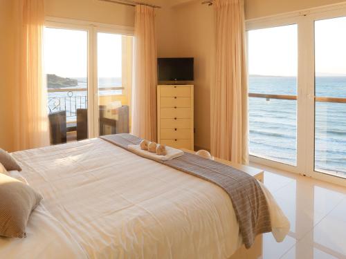 a bedroom with a bed with a view of the ocean at Pictures Suites in Agios Stefanos