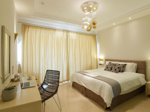 a bedroom with a bed and a desk with a laptop at Pictures Suites in Agios Stefanos
