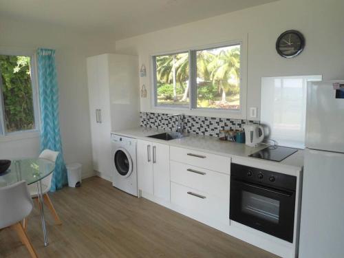 a white kitchen with a refrigerator and a dishwasher at Absolute Beachfront - A Slice of Paradise! in Rarotonga