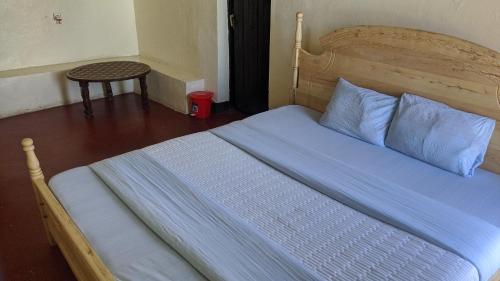 a bedroom with a bed with blue sheets and a table at Ignite guest and apartment in Rubavu